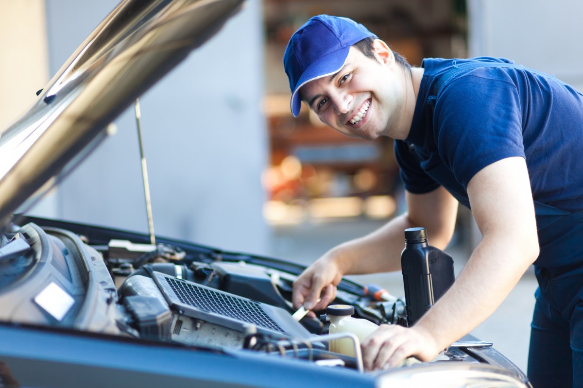 Mechanic working on car and smiling 