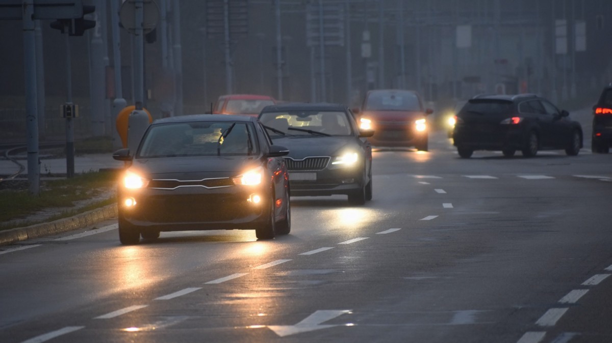 Cars driving on road with wipers and headlights on