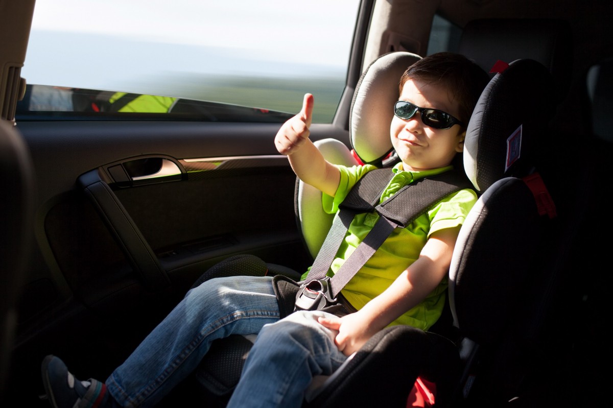 kid with a thumbs up in a car seat